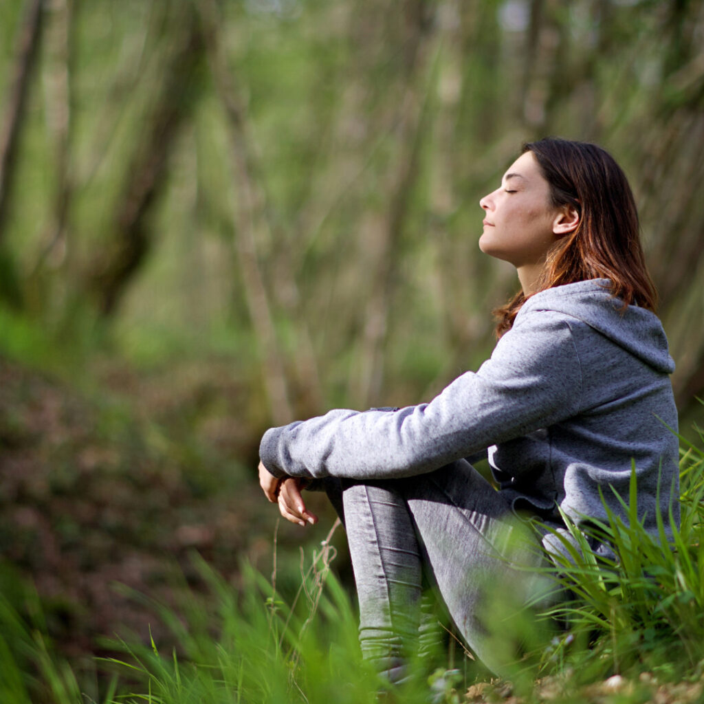 Meditation im Wald Frau meditierte sitzend im Gras bei Sonnenschein